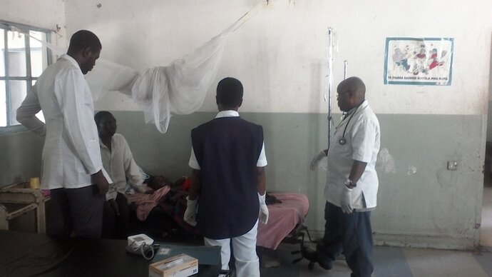 Photo: Dr Fayulu (right) and Male ward team discuss the case of a severe malaria patient.
